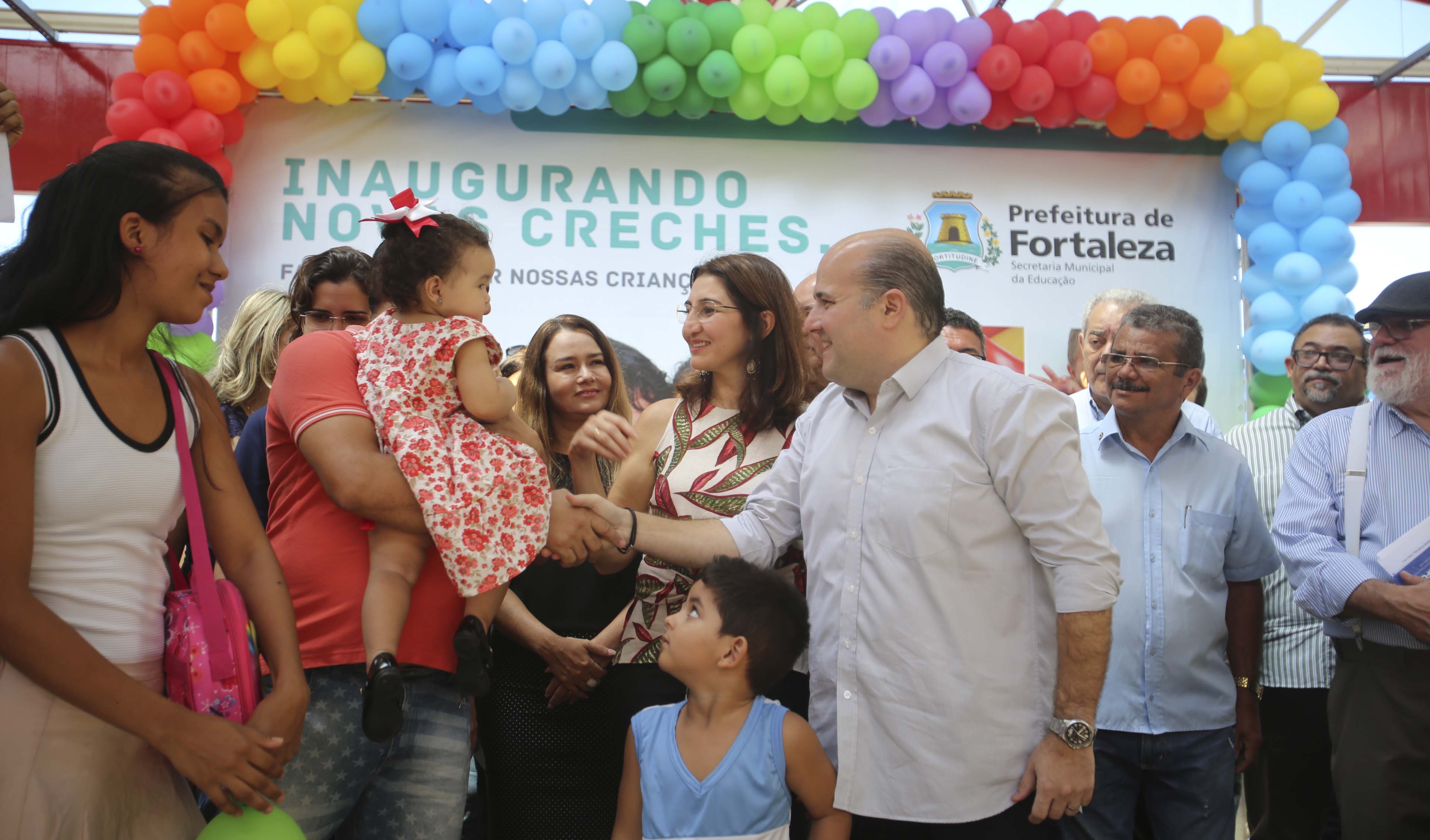 prefeito roberto cláudio fala com uma criança que está no colo do pais